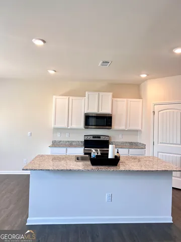 a kitchen with granite countertop a stove a sink and a microwave