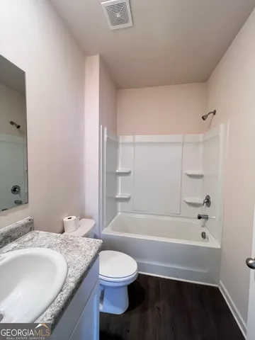 a bathroom with a granite countertop bathtub sink vanity mirror and toilet