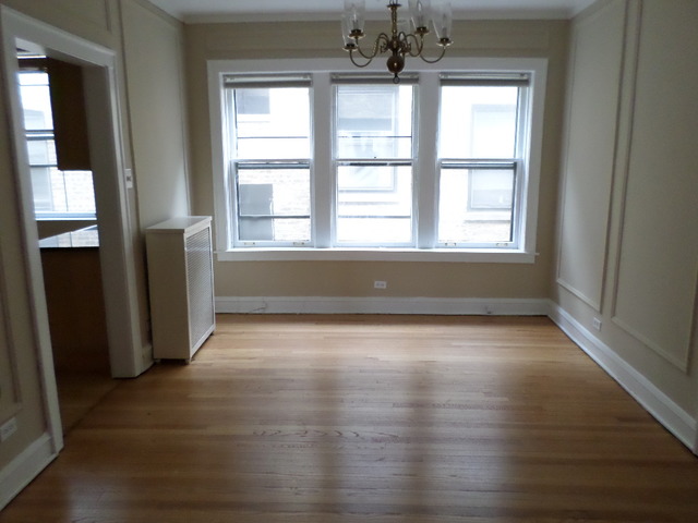 1011 Hull Terrace, Unit 22 Evanston, IL 60202 - Photo 4 of 10 an empty room with wooden floor and windows