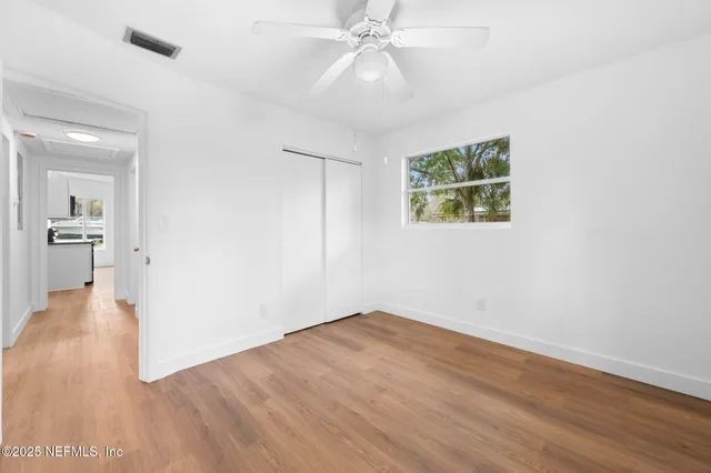 an empty room with wooden floor and windows