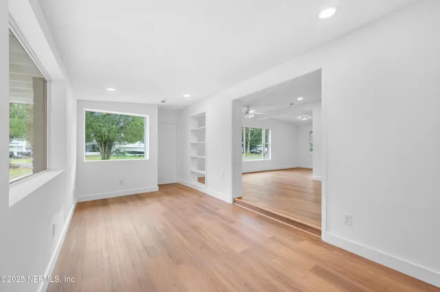 an empty room with wooden floor and windows
