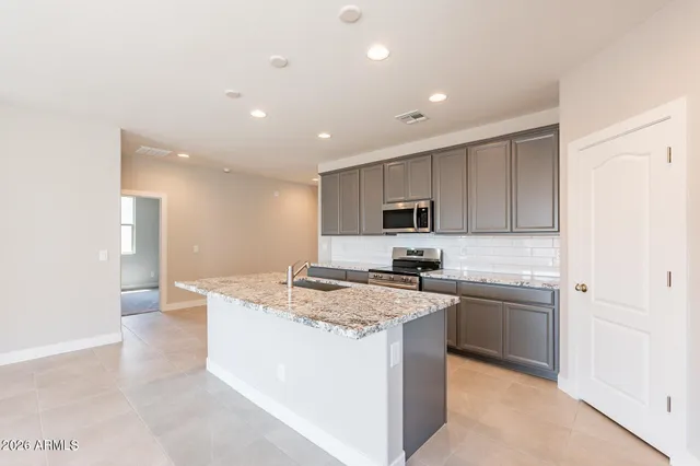 a kitchen with stainless steel appliances granite countertop a sink a stove a refrigerator and cabinets