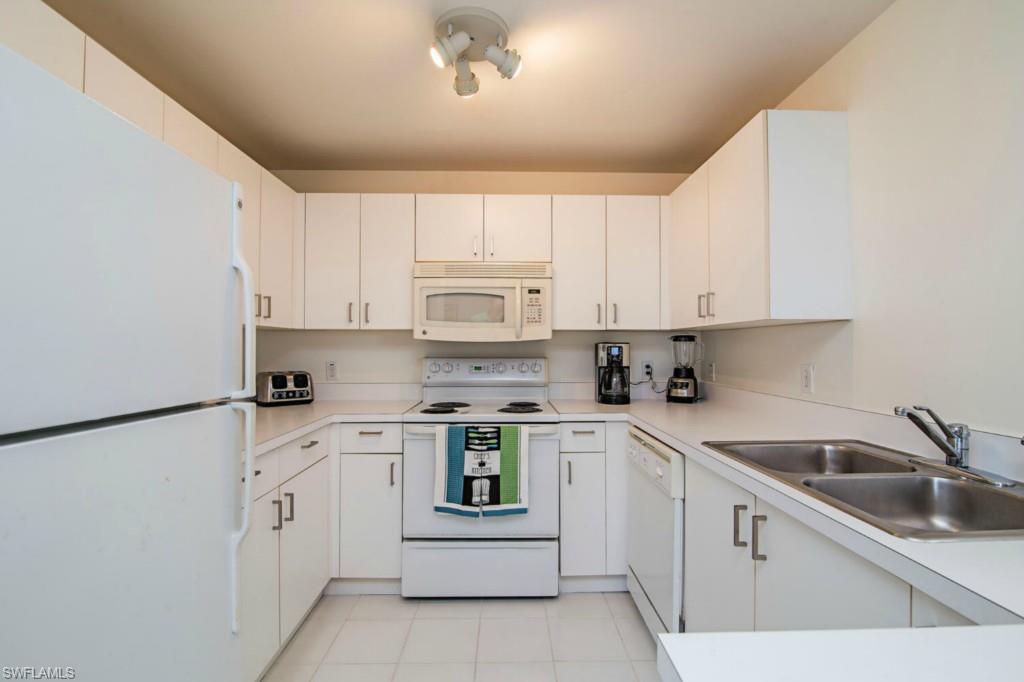 519 Roma Court, Unit 3301 Naples, FL 34110 - Photo 5 of 14 a kitchen with white cabinets white appliances and sink