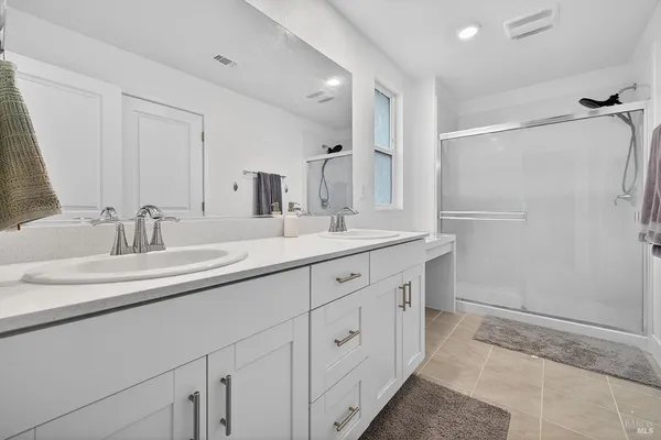 a bathroom with a double vanity sink a mirror and a shower