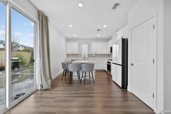 a kitchen with stainless steel appliances granite countertop a refrigerator a stove top oven and a dining table with wooden floor