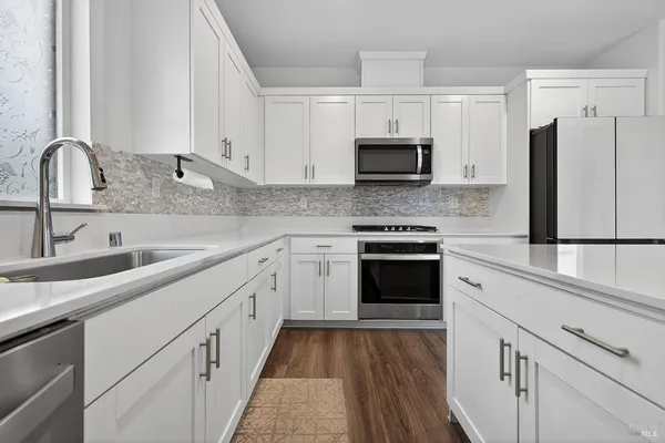 a kitchen with white cabinets sink and stainless steel appliances