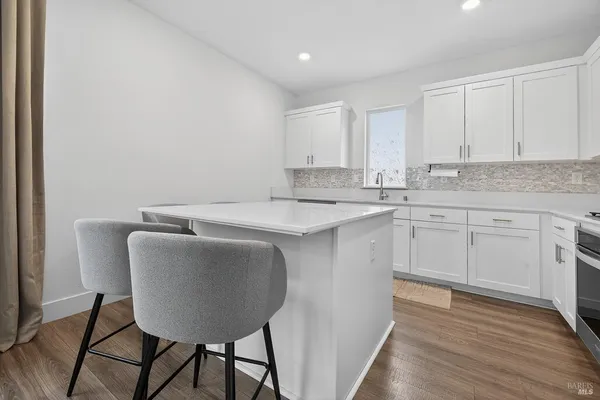 a kitchen with stainless steel appliances granite countertop a sink a stove a refrigerator with white cabinets and wooden floor