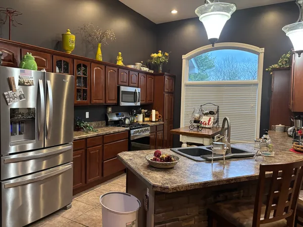 a kitchen with kitchen island granite countertop a sink appliances and cabinets