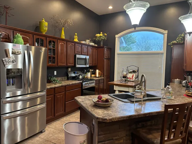 a kitchen with kitchen island granite countertop a sink appliances and cabinets