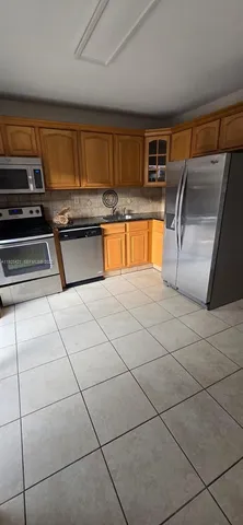 a kitchen with granite countertop a refrigerator and a stove top oven