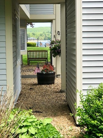 204 Beacon Park Road, Unit 204 Webster, MA 01570 - Photo 23 of 29 a garden with a bench in front of the house