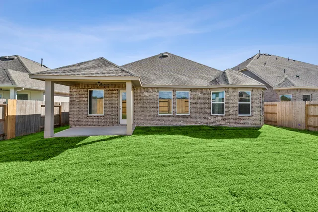 a view of a yard in front of a house with large windows