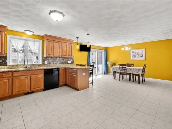 a room with stainless steel appliances granite countertop a table chairs and a refrigerator