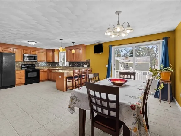 a dining hall with stainless steel appliances granite countertop a refrigerator and a sink