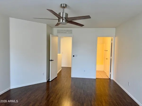 a view of empty room with wooden floor and fan