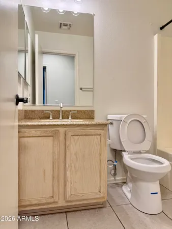 a bathroom with a granite countertop toilet sink and mirror