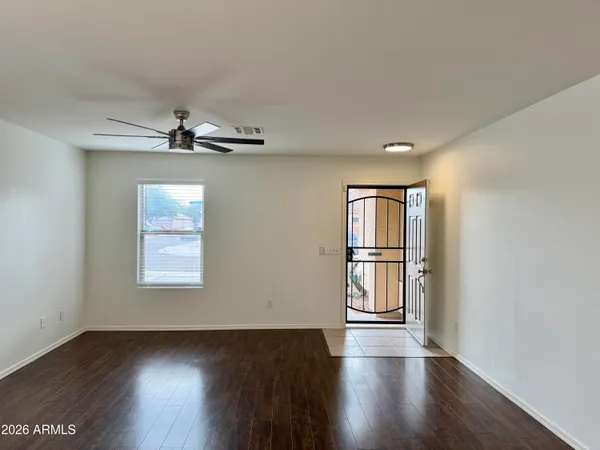 an empty room with wooden floor chandelier and windows