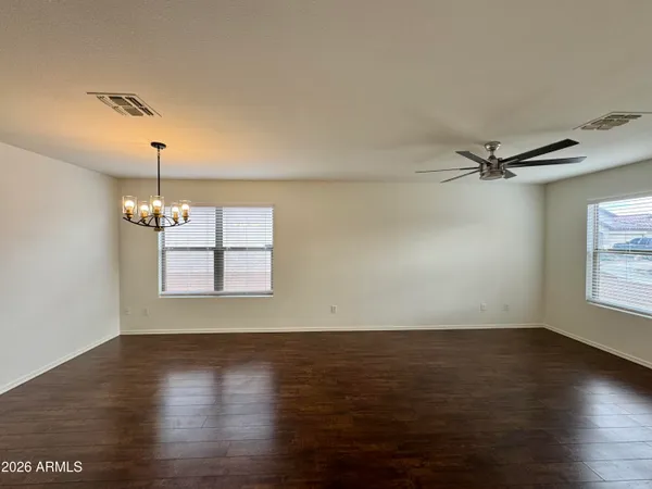 an empty room with wooden floor windows and ceiling fan