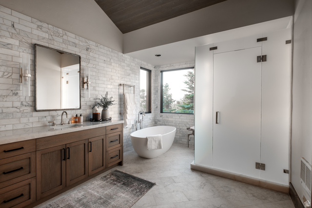 9156 Forest Road, Unit 24 Heber City, UT 84036 - Photo 16 of 42 Spacious bathroom featuring a freestanding soaking tub, large window, frosted glass shower enclosure, wood-finish vanity with a stone countertop, and marble-style subway tile walls