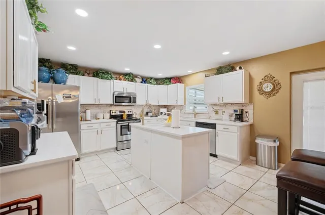 a kitchen with kitchen island granite countertop white cabinets and white appliances