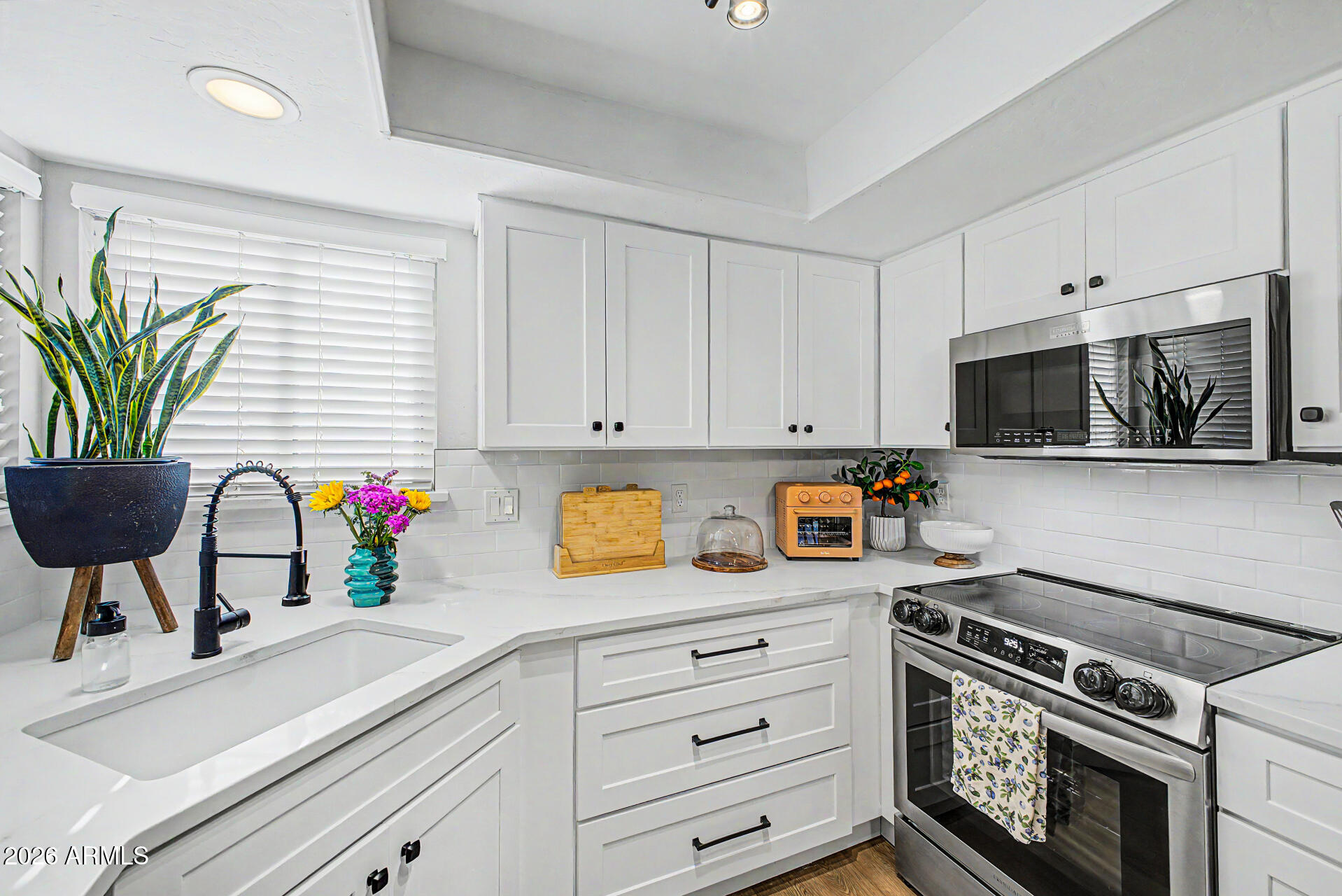 2455 East Broadway Road, Unit 65 Mesa, AZ 85204 - Photo 2 of 36 a kitchen with stainless steel appliances a sink a stove a microwave a cabinets and a potted plant