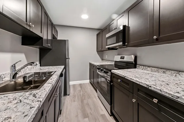 a kitchen with stainless steel appliances granite countertop a sink stove and refrigerator