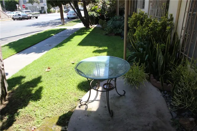 a backyard of a house with table and chairs plants and large trees