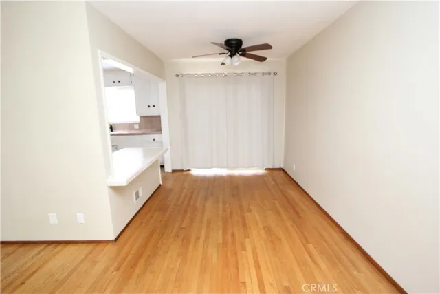 a view of a room with wooden floor and a ceiling fan