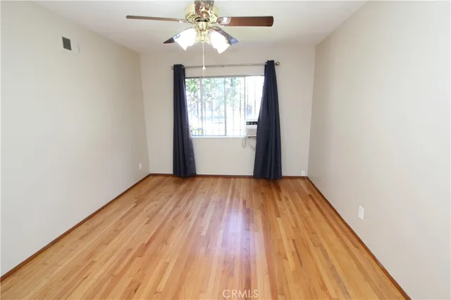 an empty room with wooden floor chandelier fan and window