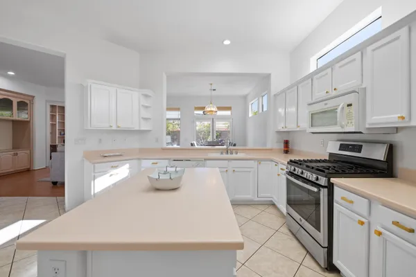 a kitchen with kitchen island granite countertop a sink a stove a oven and white cabinets