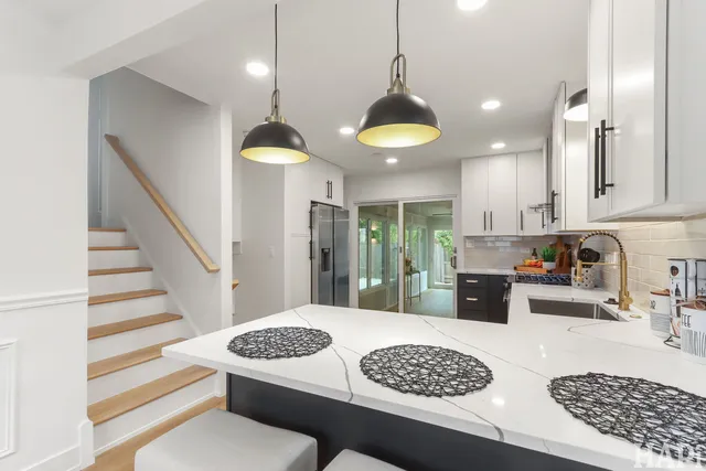 a kitchen with a stove a refrigerator a sink a dining table and chairs with wooden floor