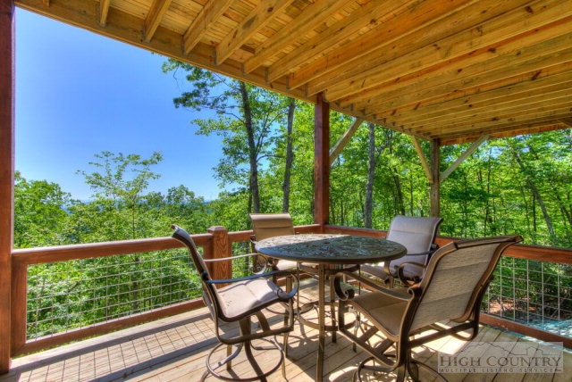 14 Goldenrod Road Boone, NC 28607 - Photo 3 of 16 a view of a patio with table and chairs and floor to ceiling window with wooden fence