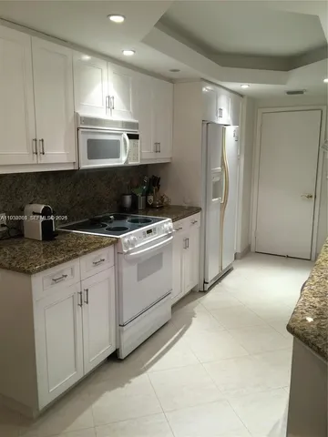a kitchen with white cabinets and refrigerator