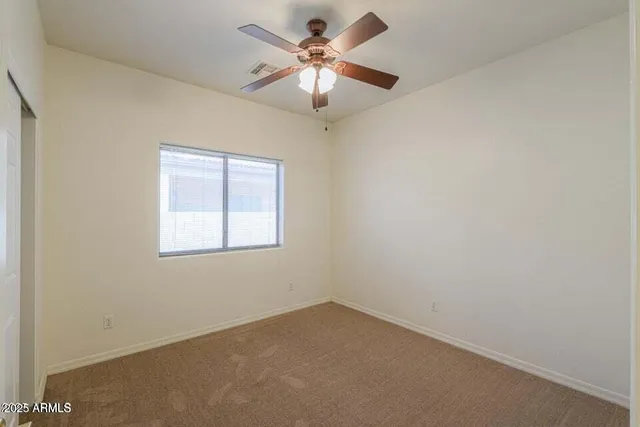 an empty room with windows and fan