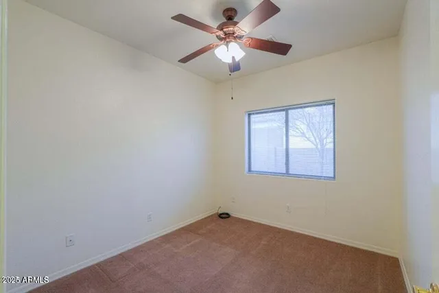 an empty room with a chandelier fan and windows