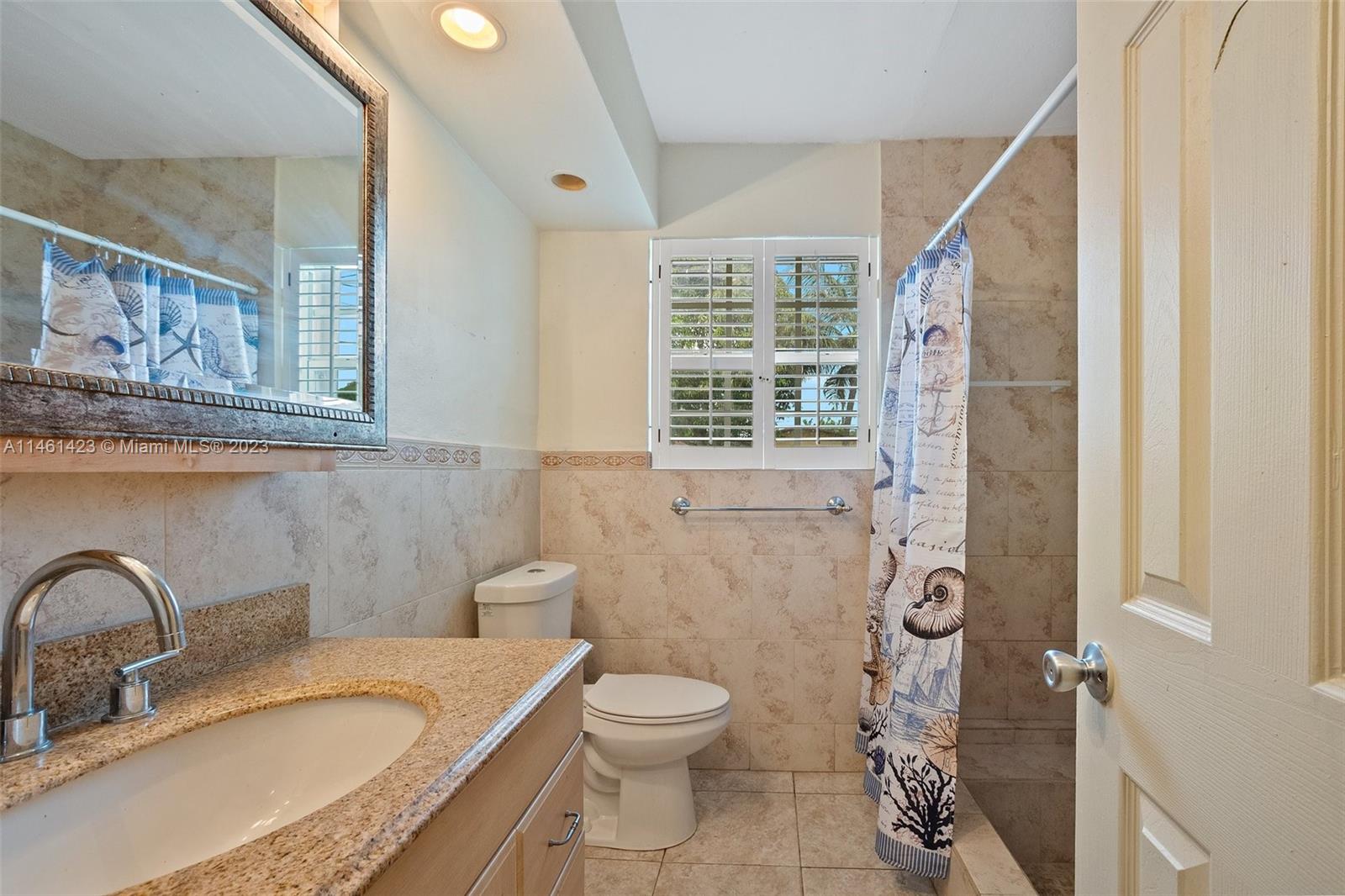 3405 East Shore Road Miramar, FL 33023 - Photo 19 of 25 a bathroom with a granite countertop toilet a sink and a mirror