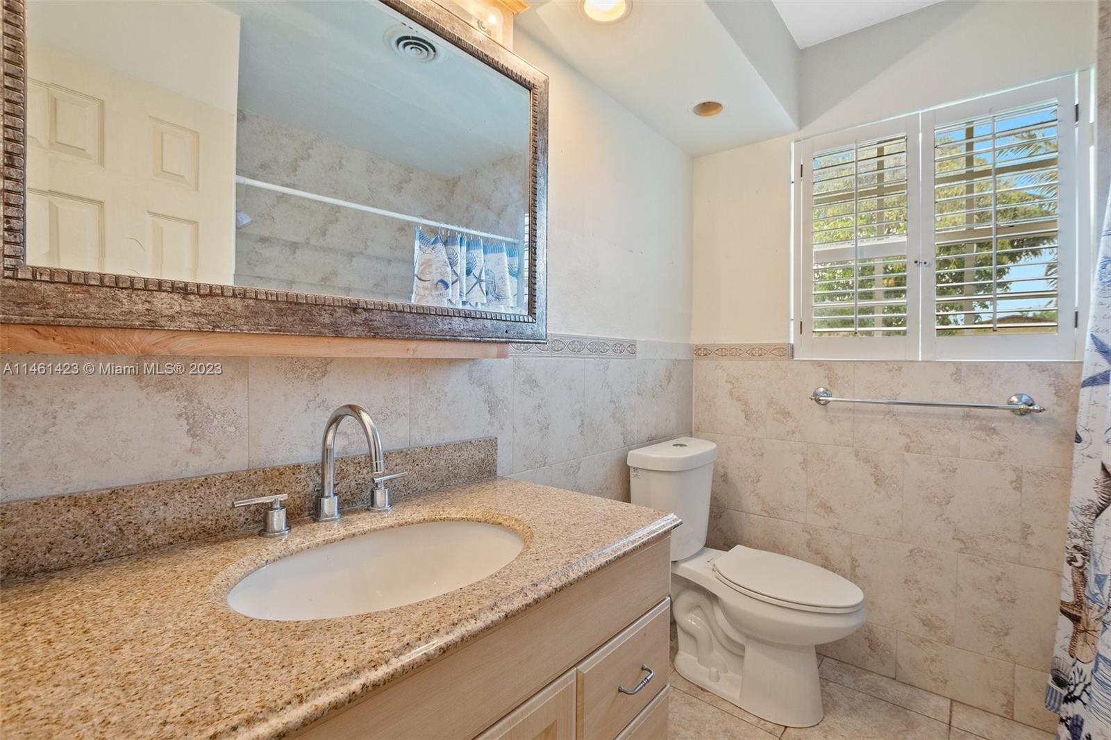 3405 East Shore Road Miramar, FL 33023 - Photo 20 of 25 a bathroom with a granite countertop toilet a sink and a mirror