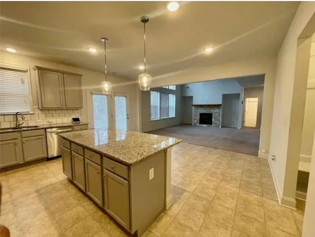 a kitchen with stainless steel appliances granite countertop a sink a counter top space cabinets and a fireplace