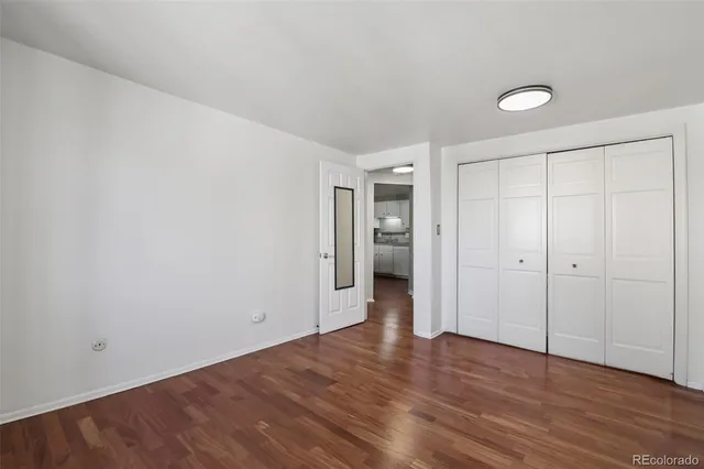 a view of an empty room with wooden floor and closet area
