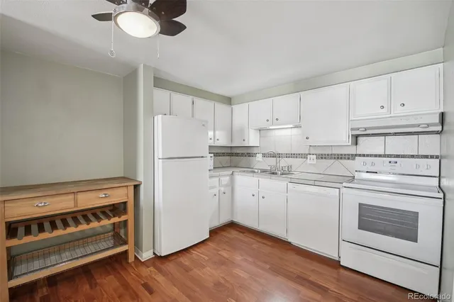 a kitchen with granite countertop white cabinets and white appliances