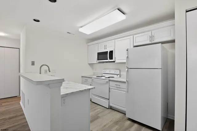 a kitchen with stainless steel appliances a refrigerator sink and white cabinets