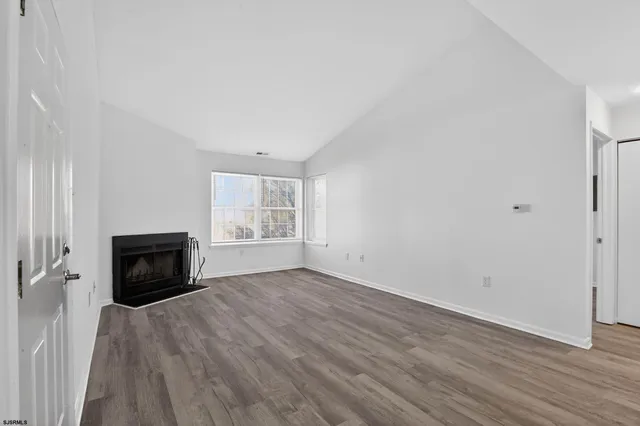 an empty room with wooden floor fireplace and windows