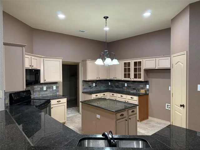 a kitchen with stainless steel appliances granite countertop a stove a sink dishwasher a refrigerator white cabinets and wooden floor