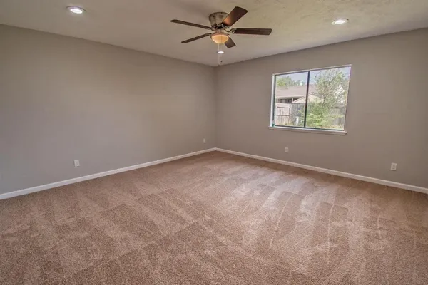 an empty room with a window and a fan