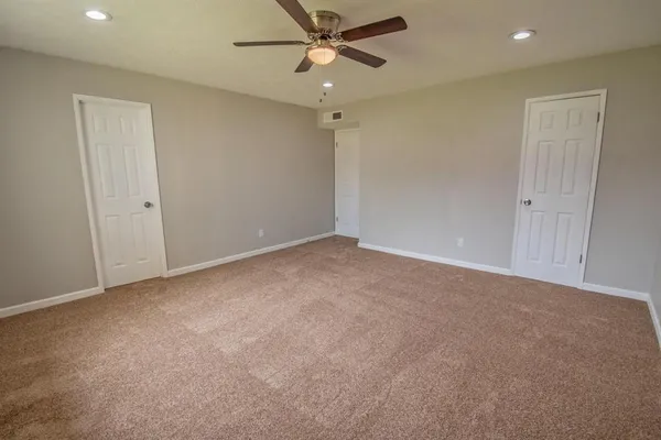an empty room with a ceiling fan and a window
