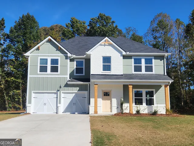 a front view of a house with yard and trees in the background