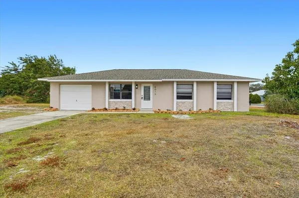 a front view of house with yard and trees in the background
