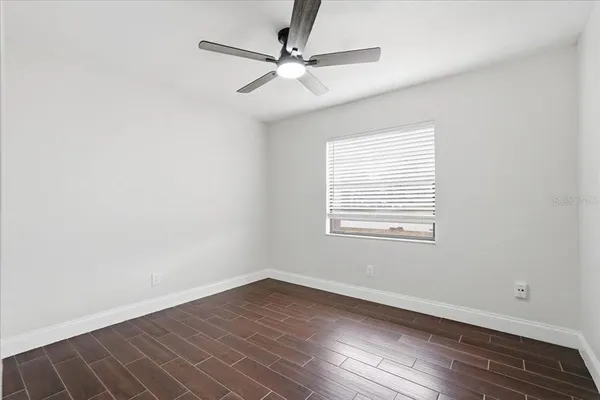 an empty room with wooden floor fan and windows