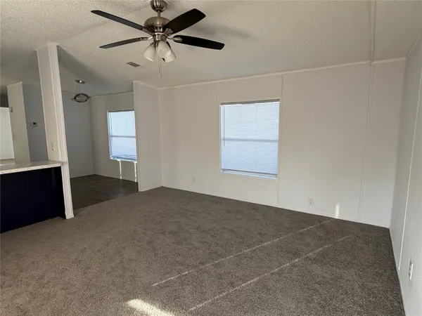 an empty room with windows and fan