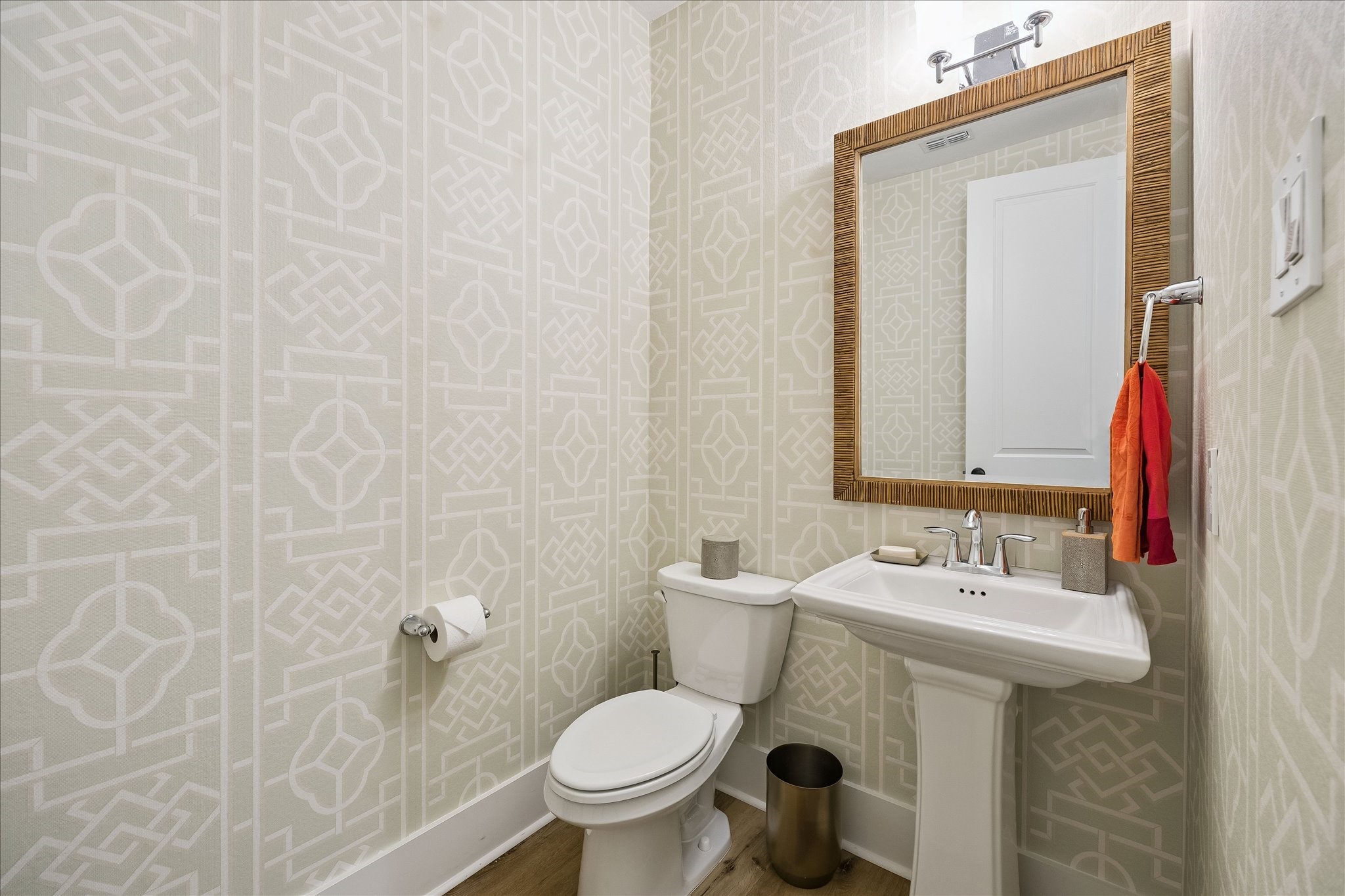 2512 Swang Pl. Houston, TX 77008 - Photo 20 of 46 This stylish powder room features patterned wallpaper, a pedestal sink, large framed mirror, elegant lighting, and tasteful decor, creating a fresh and inviting space.